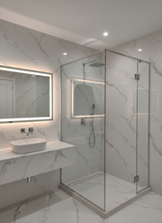 Modern bathroom with marble walls, a shower, and sink.