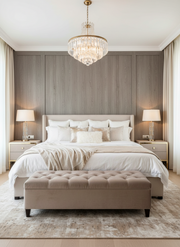Neatly made bed with white bedding in a bedroom setting, featuring a chandelier and side lamps.